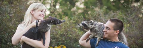 Two people each holding one animal